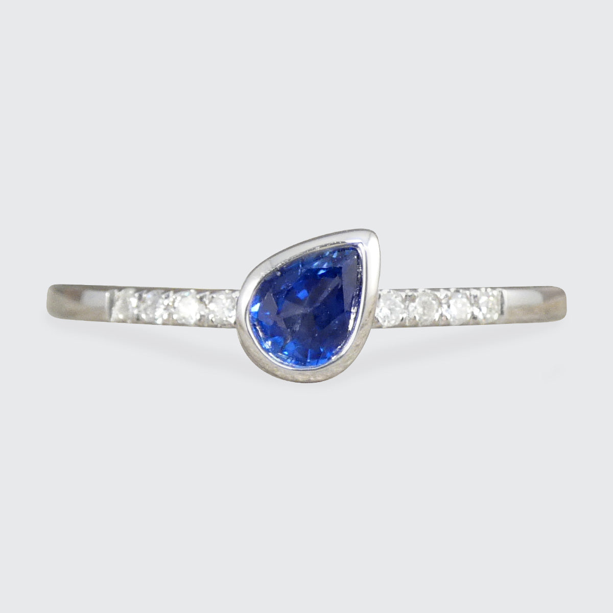 A pear cut Sapphire solitaire ring with diamonds set into the band as shoulders in 18ct white gold.