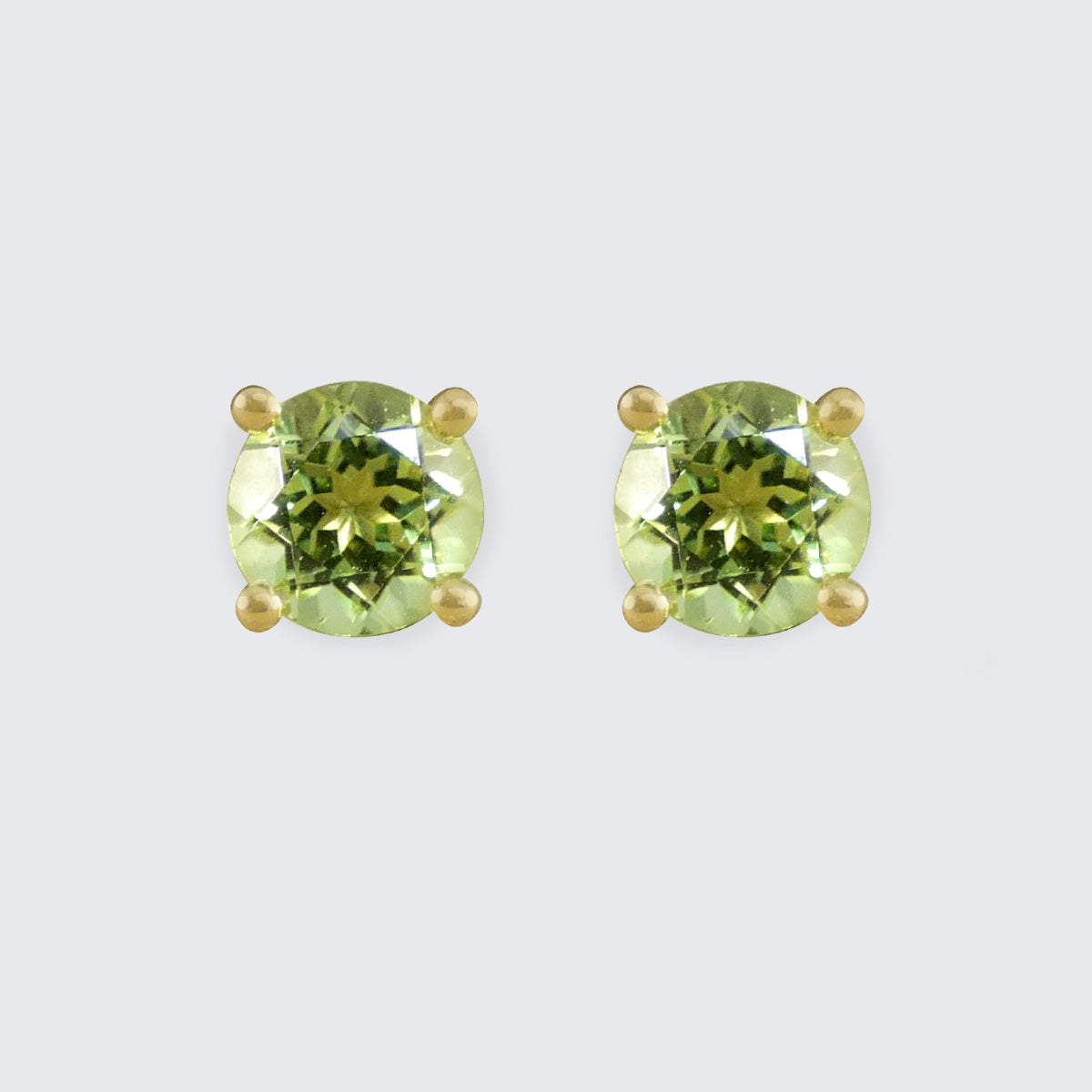 Four-claw peridot stud earrings crafted in 9ct yellow gold, featuring vibrant round-cut green gemstones with a classic and elegant design