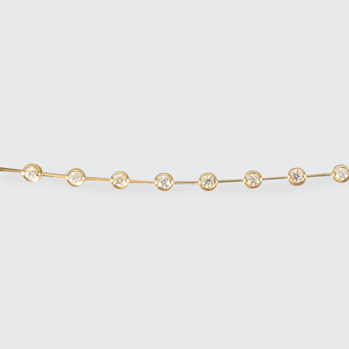 Delicate 18ct yellow gold diamond bracelet featuring bezel-set brilliant-cut diamonds evenly spaced along a sleek chain, perfect for adding timeless elegance to any outfit.