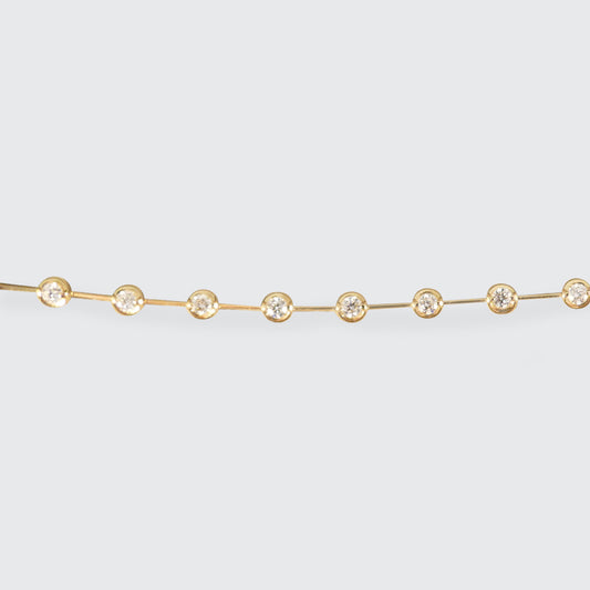 Delicate 18ct yellow gold diamond bracelet featuring bezel-set brilliant-cut diamonds evenly spaced along a sleek chain, perfect for adding timeless elegance to any outfit.