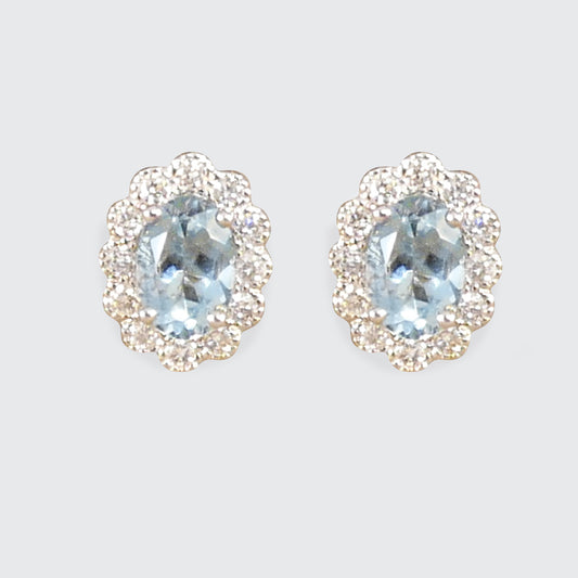 Aquamarine and Diamond cluster earring sin 18ct white and yellow gold. Light to medium oval cut aquamarines in a four claw setting with smaller brilliant cut diamonds creating lots of sparkle.