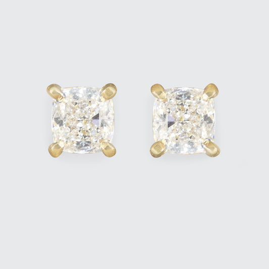 GIA-certified high-colour cushion-cut diamond stud earrings, set in 18ct yellow gold with a classic four-claw design for timeless elegance.