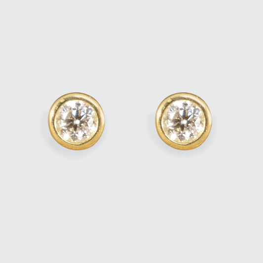 Elegant 0.40ct total brilliant-cut diamond stud earrings, set in sleek bezel settings crafted from polished yellow gold, showcasing timeless sophistication.