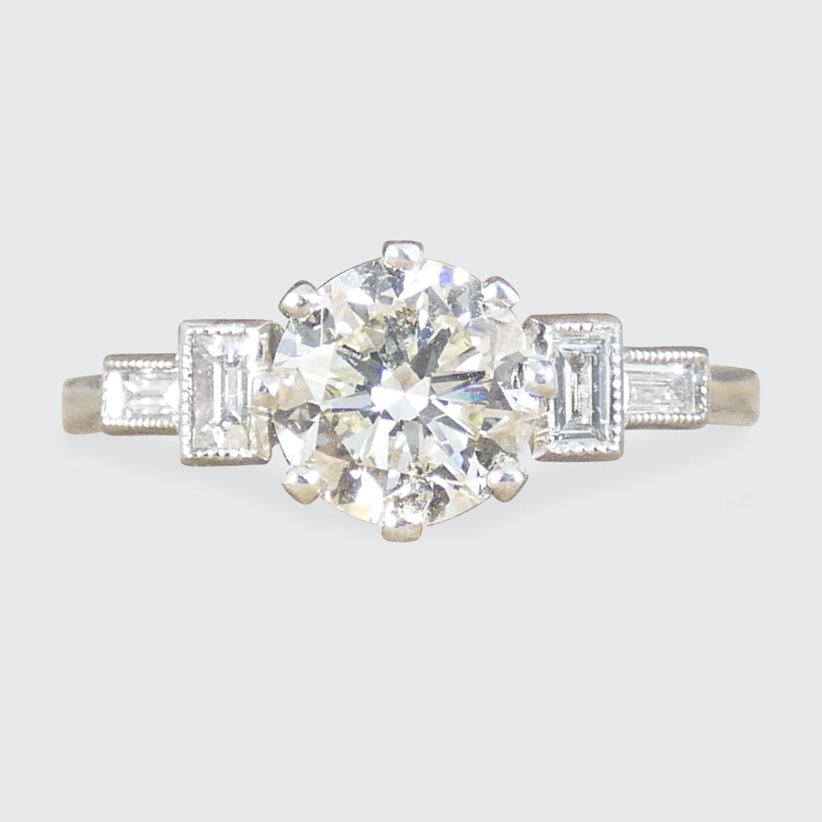 Art Deco homage engagement ring with an early brilliant cut centre and baguette cut diamond shoulders set in Platinum.