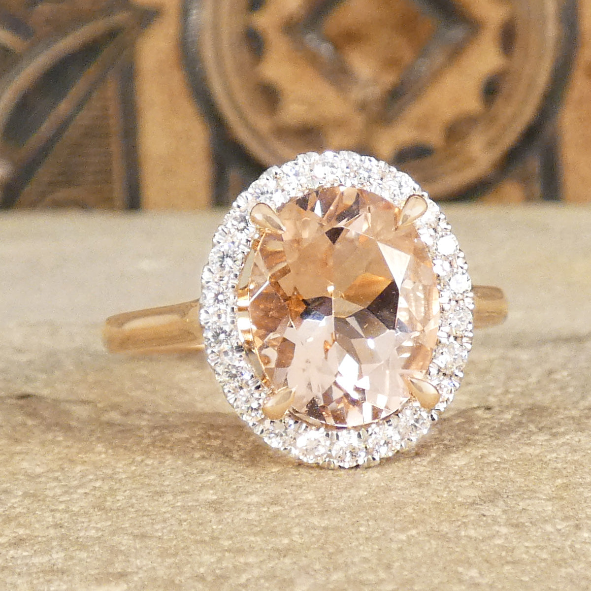 2.51ct Oval Cut Morganite and Diamond Halo cluster ring in 18ct White and Rose gold. The Morganite is showing a lovely peachy pink hue with a four spiked claw setting.