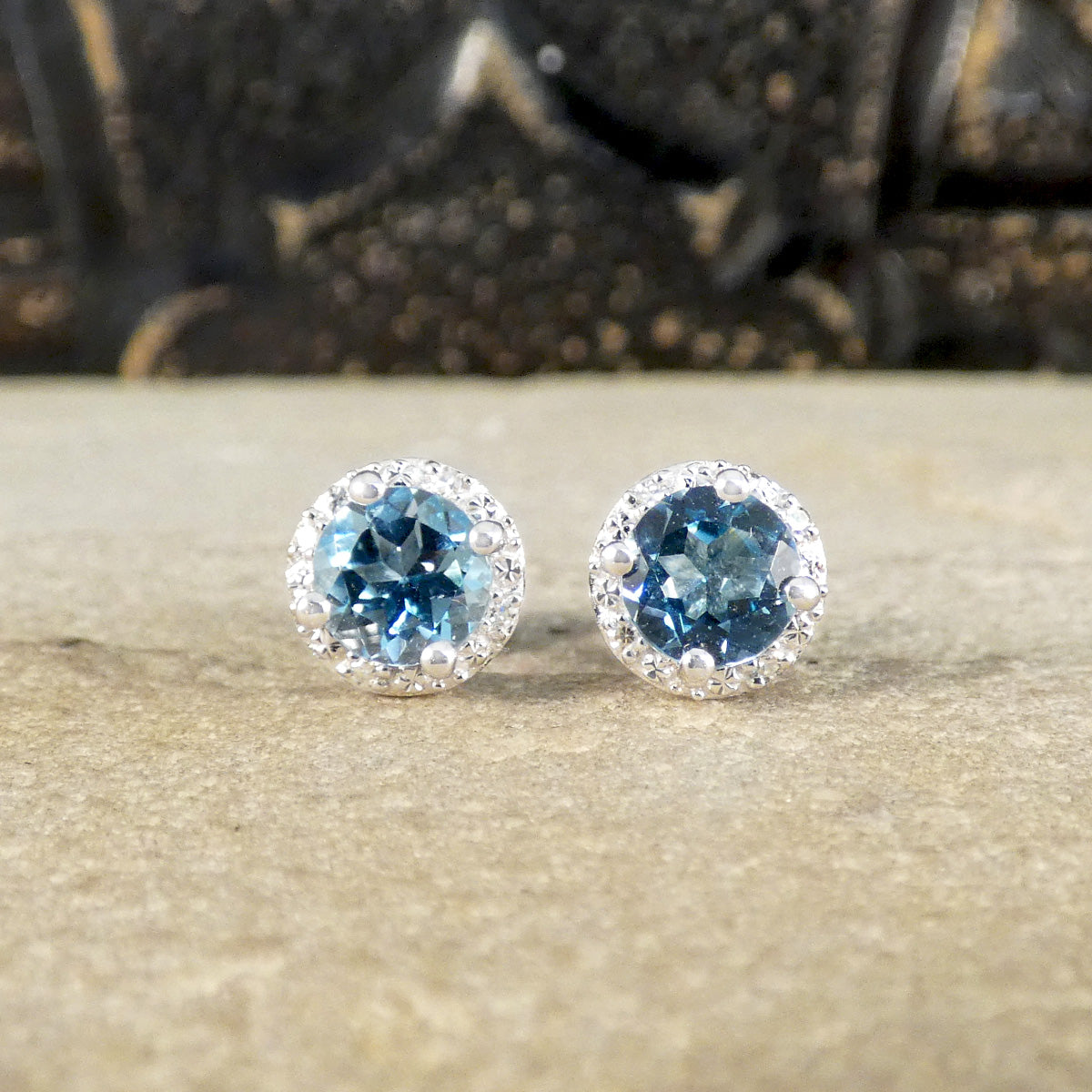 Bright blue Topaz set in a four claw setting with an illusion diamond halo creating sparkle.