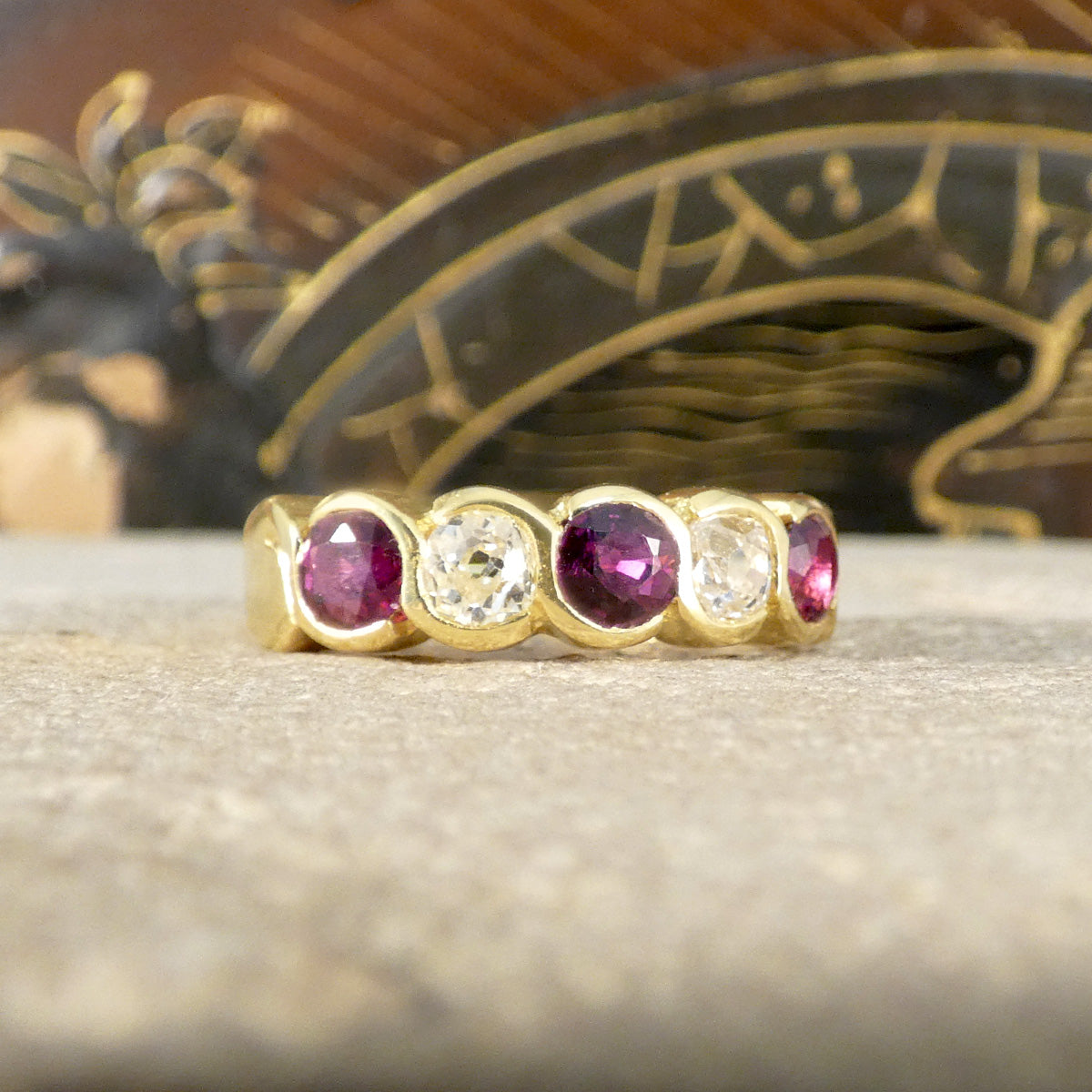 Vintage five-stone ring showcasing vibrant rubies and sparkling diamonds in a bold, chunky design, crafted in 18ct yellow gold with a waved bezel setting.