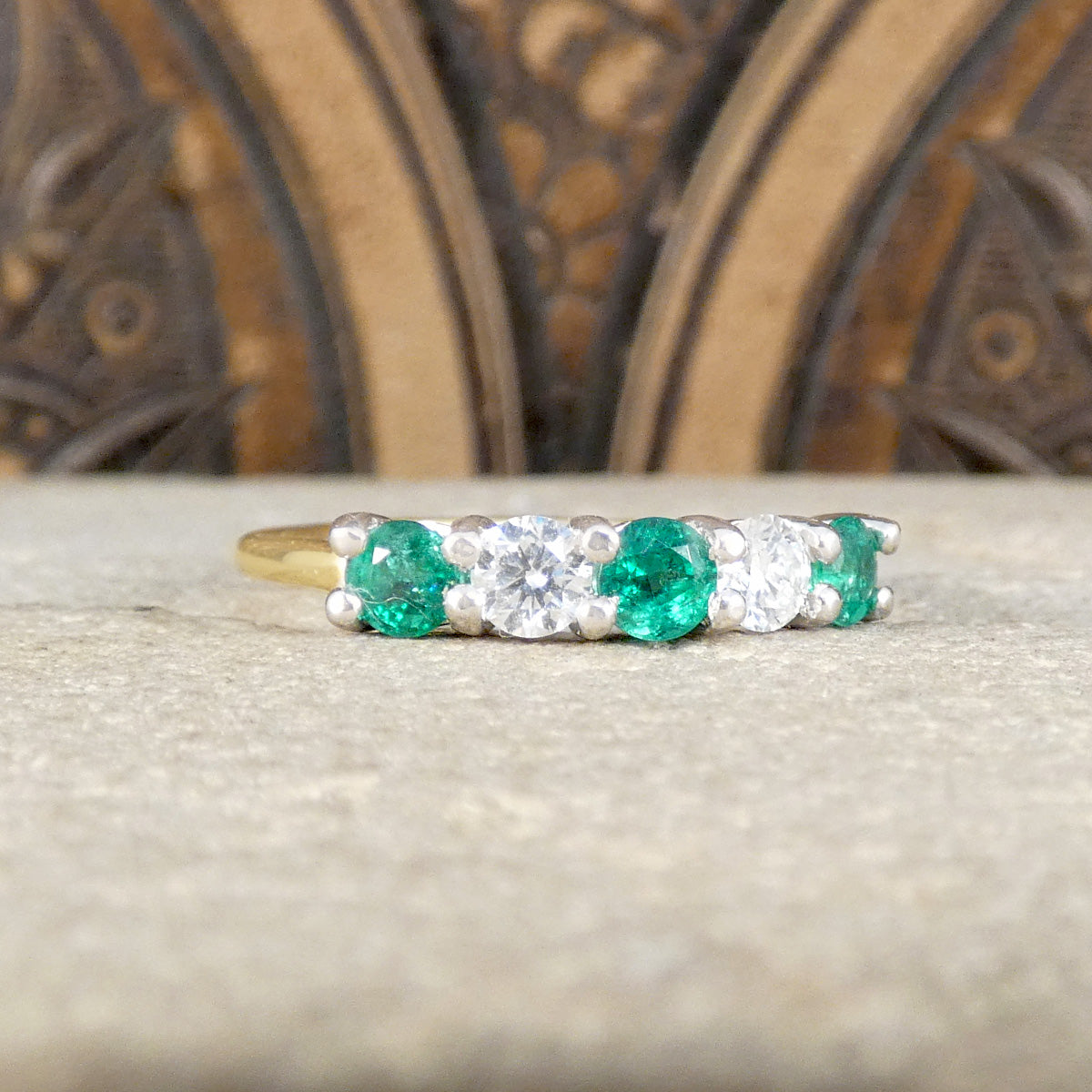 Featuring bright and vibrant emeralds sandwiching bright and clear diamonds in a five stone band ring.