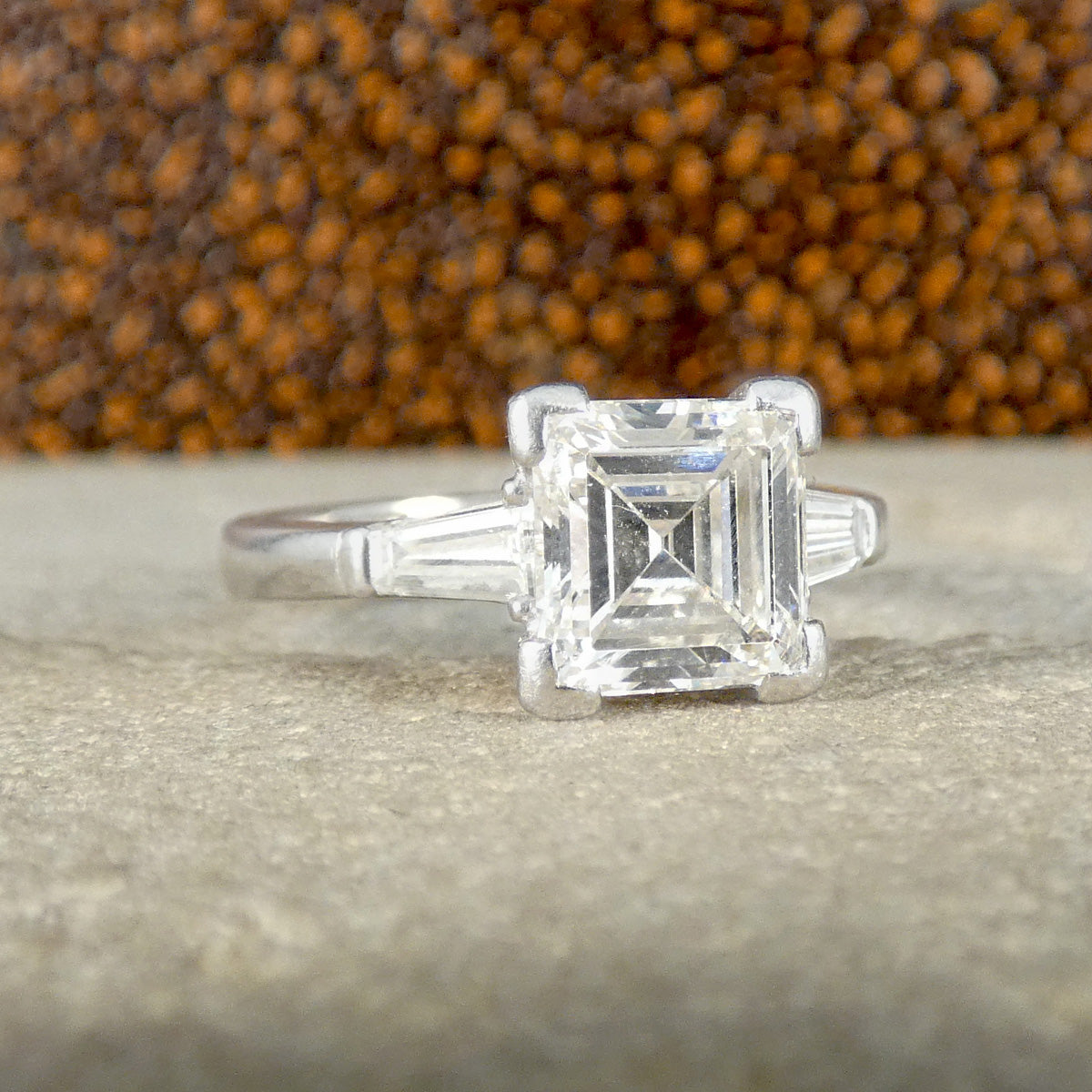 Elegant engagement ring featuring a 1.75-carat square emerald-cut diamond as the centrepiece, set in a luxurious 18-carat white gold band, with tapered baguette diamonds on each side, highlighting its sophisticated and timeless design.