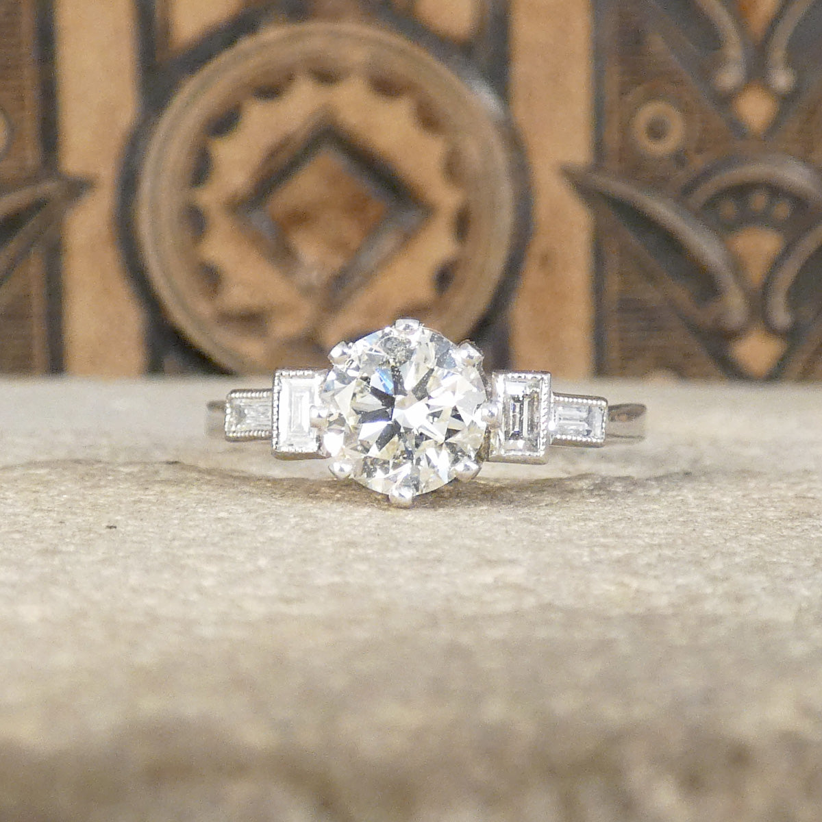 Art Deco homage engagement ring with an early brilliant cut centre and baguette cut diamond shoulders set in Platinum.