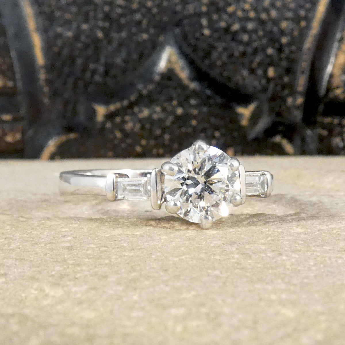 A classic brilliant cut diamond solitaire with baguette cut diamond shoulders in 18ct white gold. GIA certed diamond in a six claw setting, the perfect engagement ring.