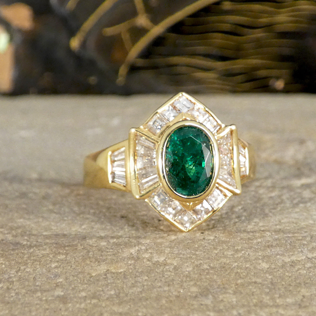 Elegant emerald and tapered diamond cluster ring set in yellow metal, testing as 18ct yellow gold, featuring a vivid oval emerald centre stone surrounded by shimmering tapered baguette diamonds.