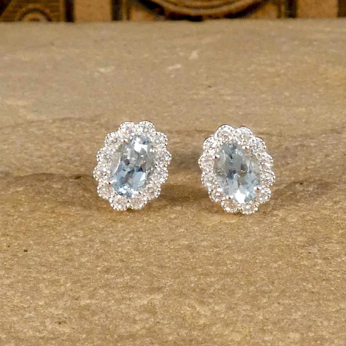 Aquamarine and Diamond cluster earring sin 18ct white and yellow gold. Light to medium oval cut aquamarines in a four claw setting with smaller brilliant cut diamonds creating lots of sparkle.