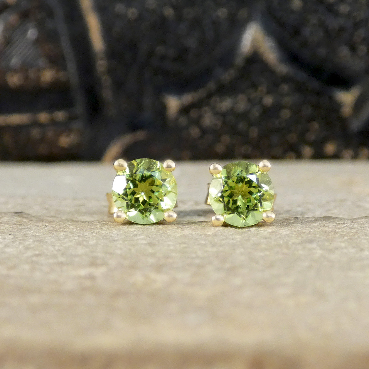 Four-claw peridot stud earrings crafted in 9ct yellow gold, featuring vibrant round-cut green gemstones with a classic and elegant design