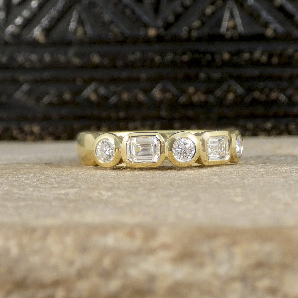 Half eternity ring with alternating emerald-cut and brilliant-cut diamonds, bezel set in 18ct yellow gold, offering a modern and sophisticated design.