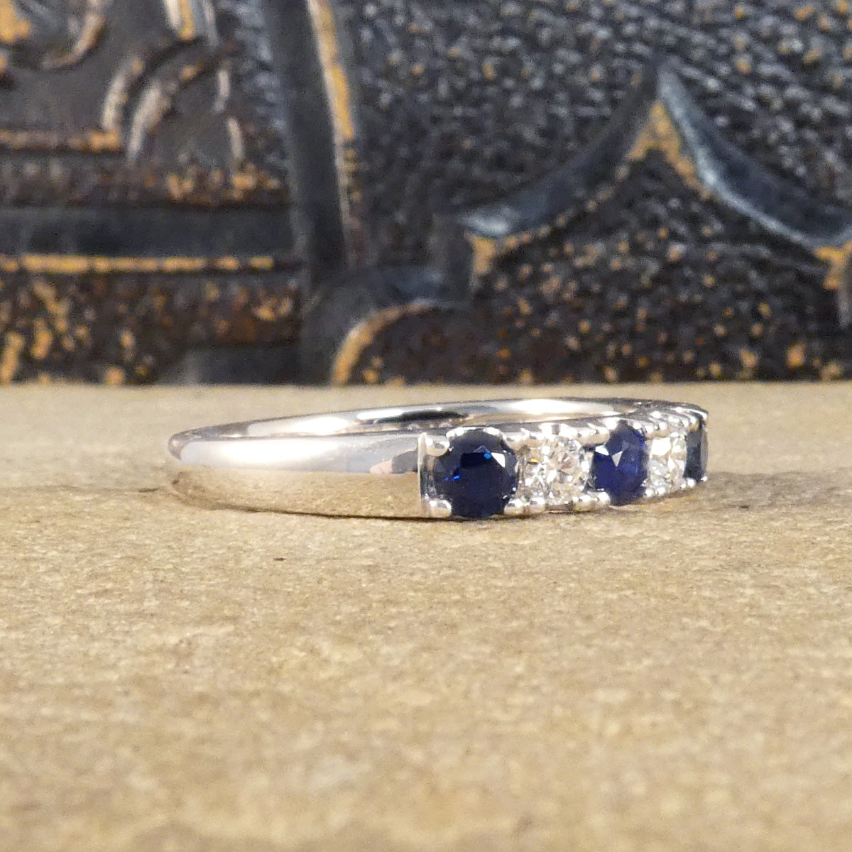 Side view of alternating blue Sapphire and Diamond half eternity ring in white gold to complement the stones.