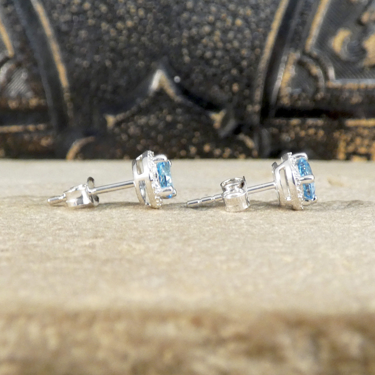 Side view of Blue Topaz and diamond cluster earrings showing butterfly backs and stems.