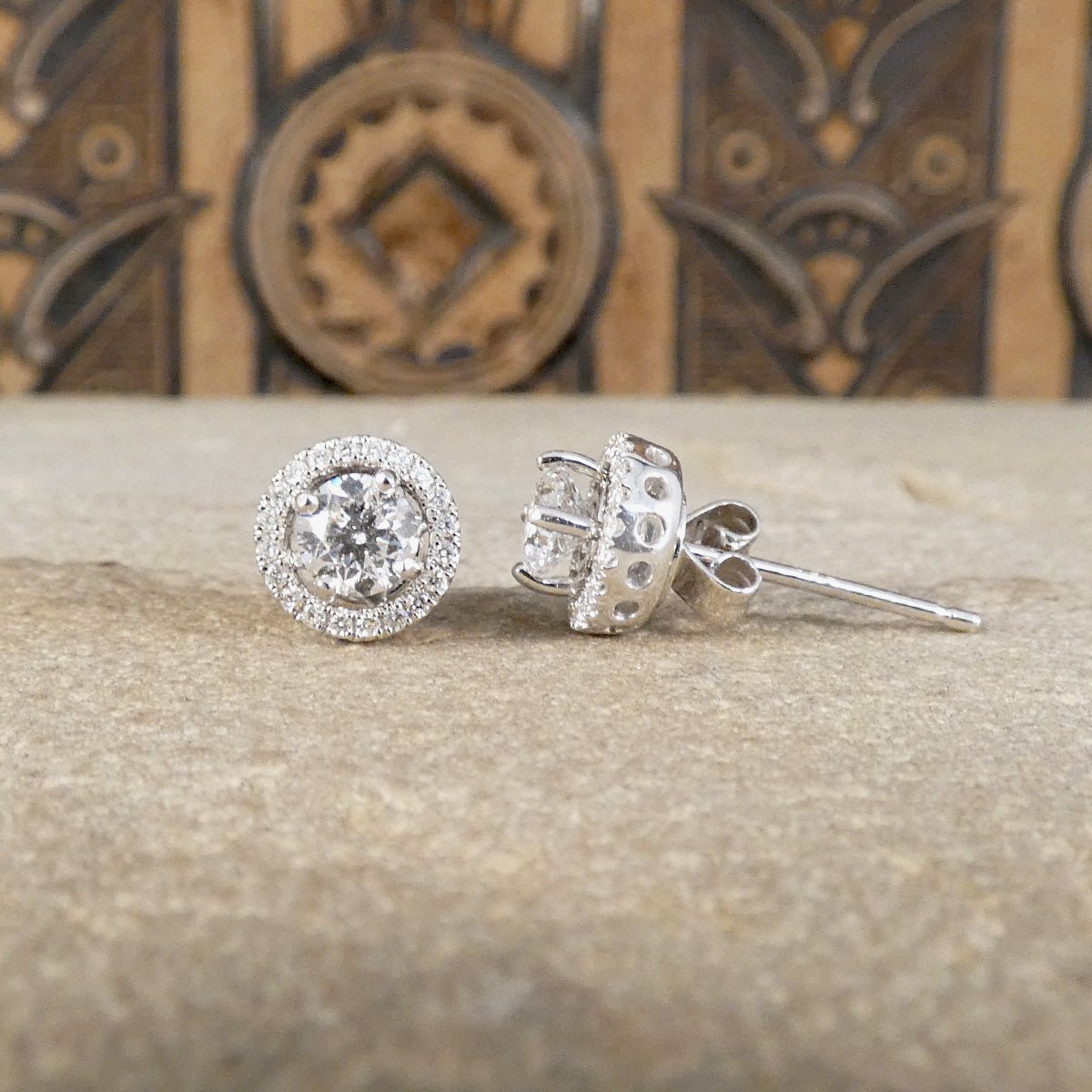 Diamond halo stud earrings from the frnt and side showing bright colour and butterfly backs in 18ct white gold.