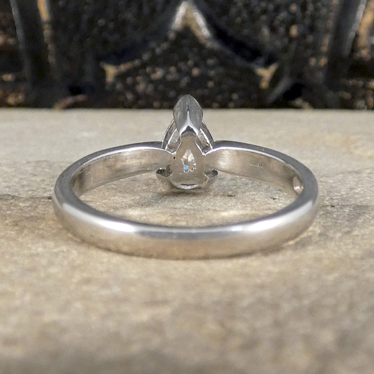 Back view of pear cut solitaire diamond ring with substantial and polished platinum band. 