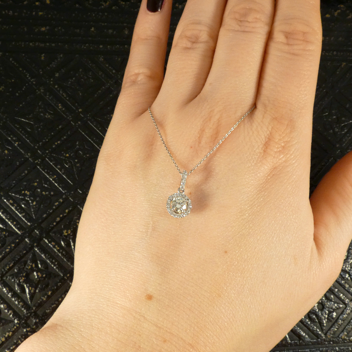 Platinum diamond halo cluster necklace elegantly worn on the hand, highlighting its refined craftsmanship and sparkling brilliance.