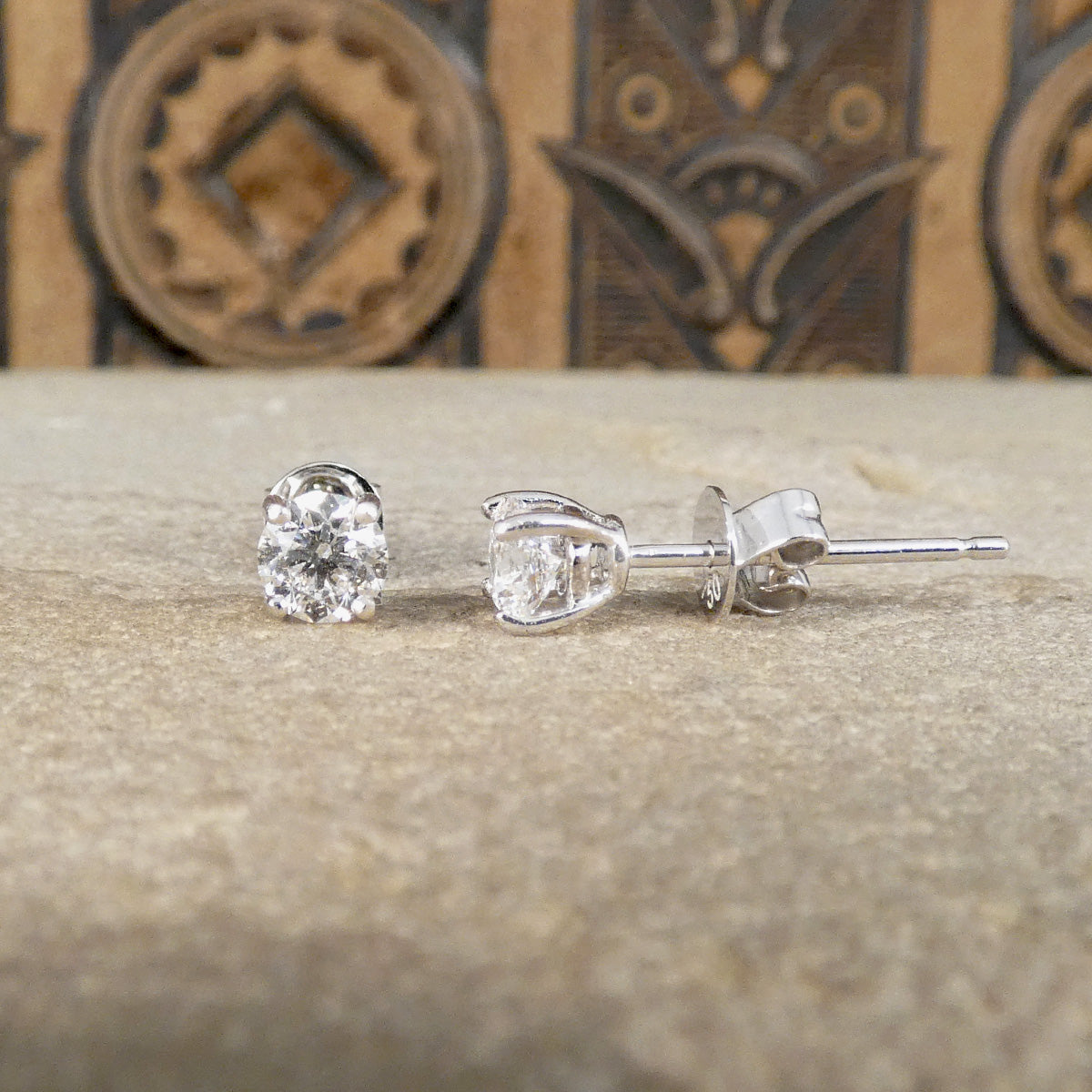 A classic pair of diamond single stud earrings, showing one rom the front and one from the side in 18ct white gold.