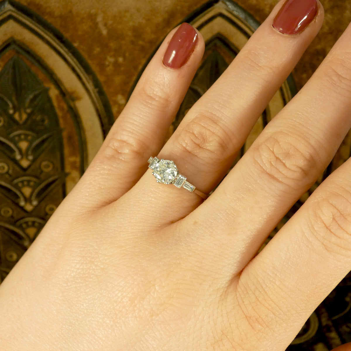 Art Deco style engagement ring with an early brilliant cut centre and baguette cut diamond shoulders set in Platinum. Shown on finger and a true vintage beauty.