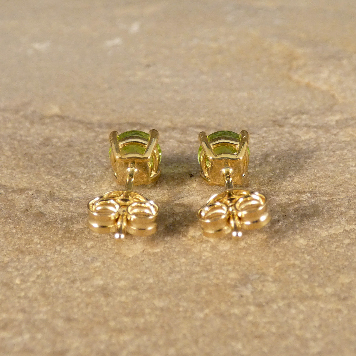 Back view of four-claw peridot stud earrings crafted in 9ct yellow gold, featuring vibrant round-cut green gemstones with a classic and elegant design