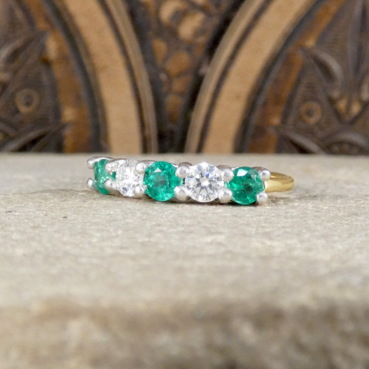 Featuring bright and vibrant emeralds sandwiching bright and clear diamonds in a five stone band ring.