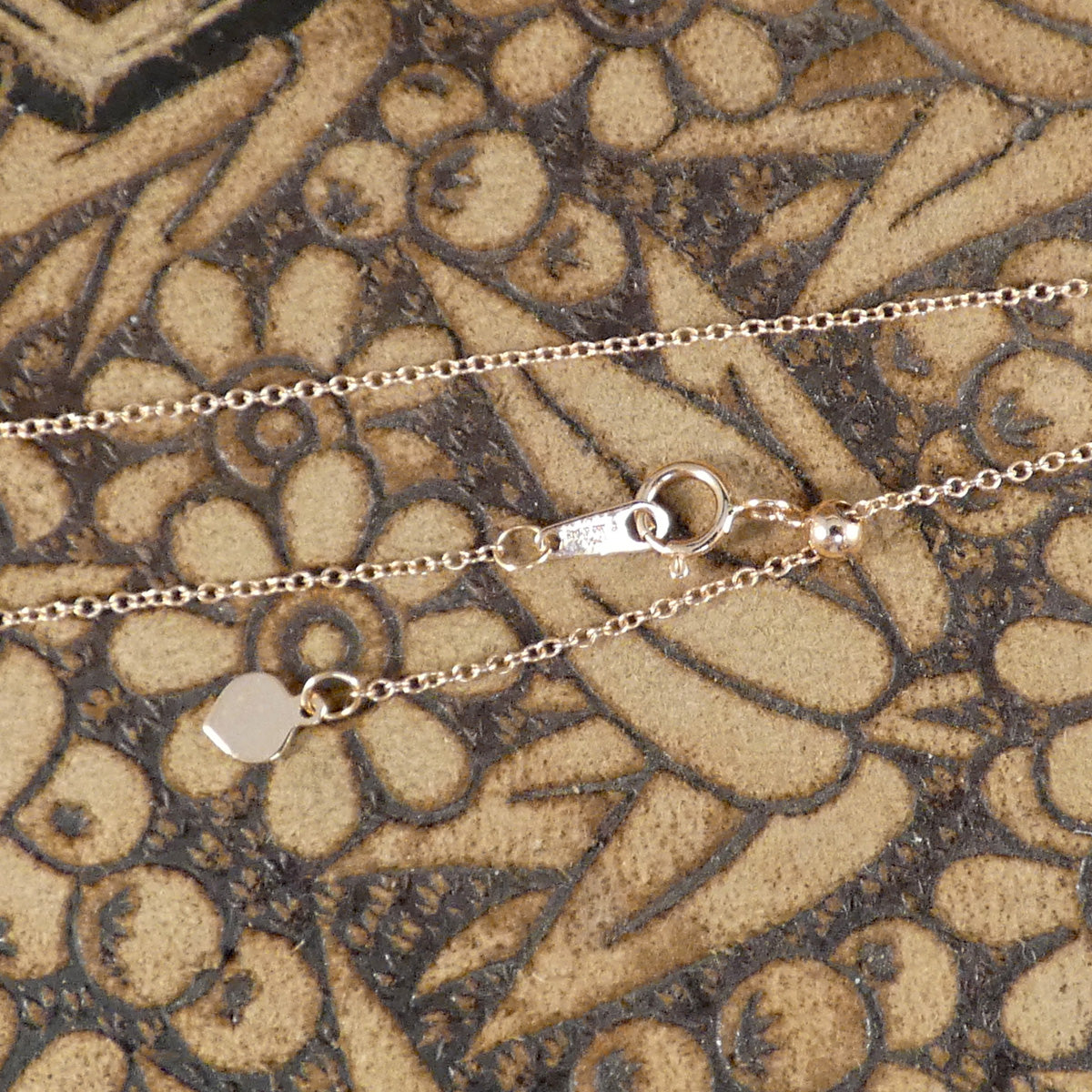 Image of clasp of the necklace with a pull alternator to change length.