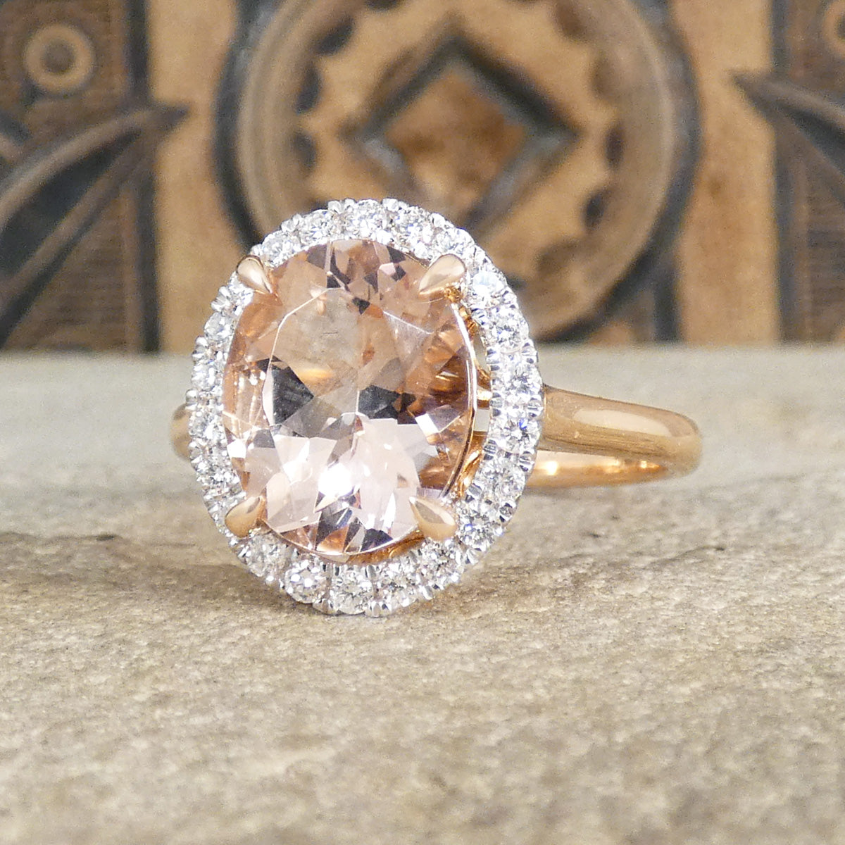 2.51ct Oval Cut Morganite and Diamond Halo cluster ring in 18ct White and Rose gold. The Morganite is showing a lovely peachy pink hue with a four spiked claw setting.