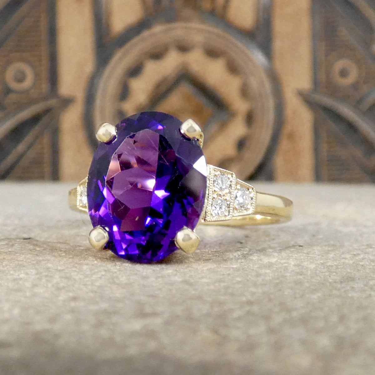 Bright and vibrant amethyst ring in a four claw setting with diamond set shoulders in 9ct yellow gold. Classic Art Deco style with a modern mount.