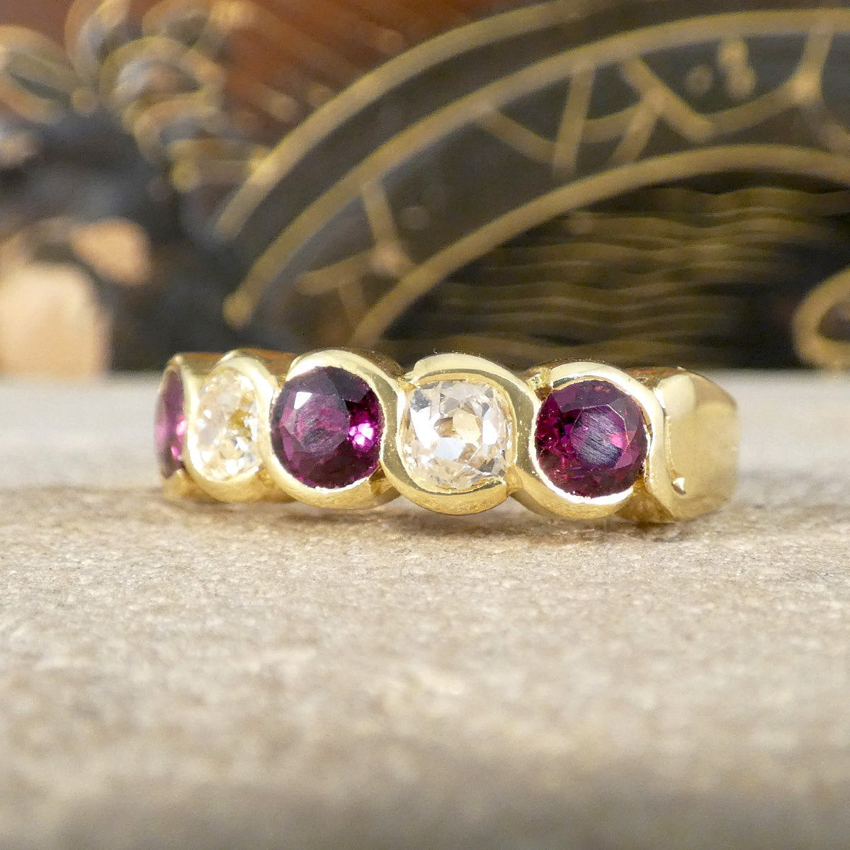 Vintage five-stone ring showcasing vibrant rubies and sparkling diamonds in a bold, chunky design, crafted in 18ct yellow gold with a waved bezel setting.