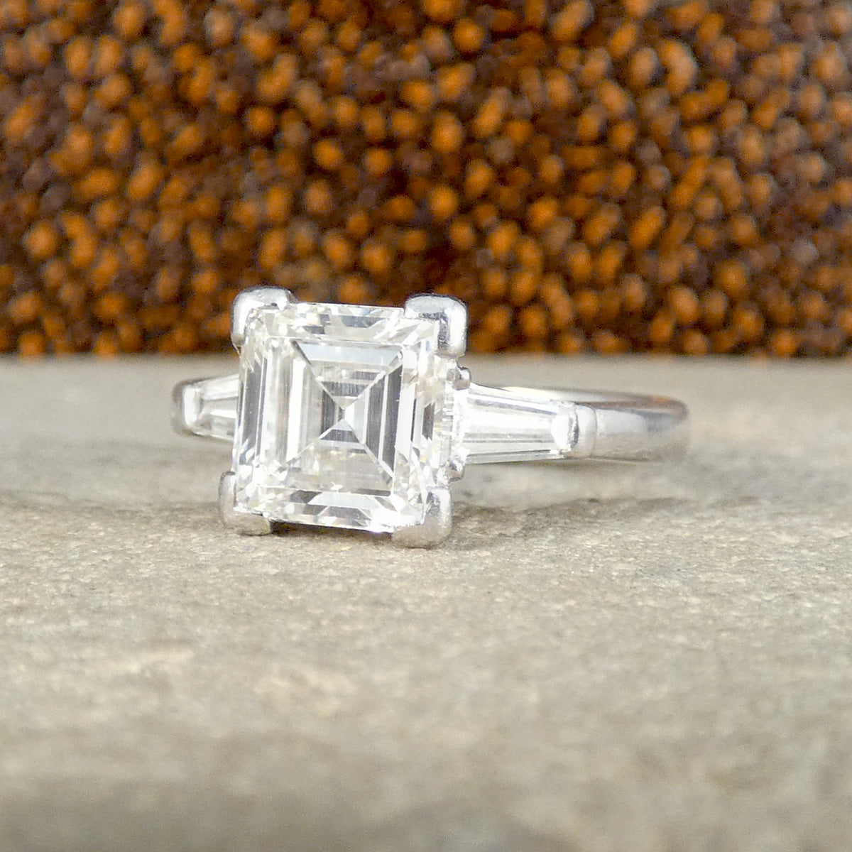 Stunning 18-carat white gold ring featuring a 2.00-carat total diamond weight, with a square emerald-cut centre diamond flanked by tapered baguette diamonds on each side, creating a classic and elegant three-stone design.