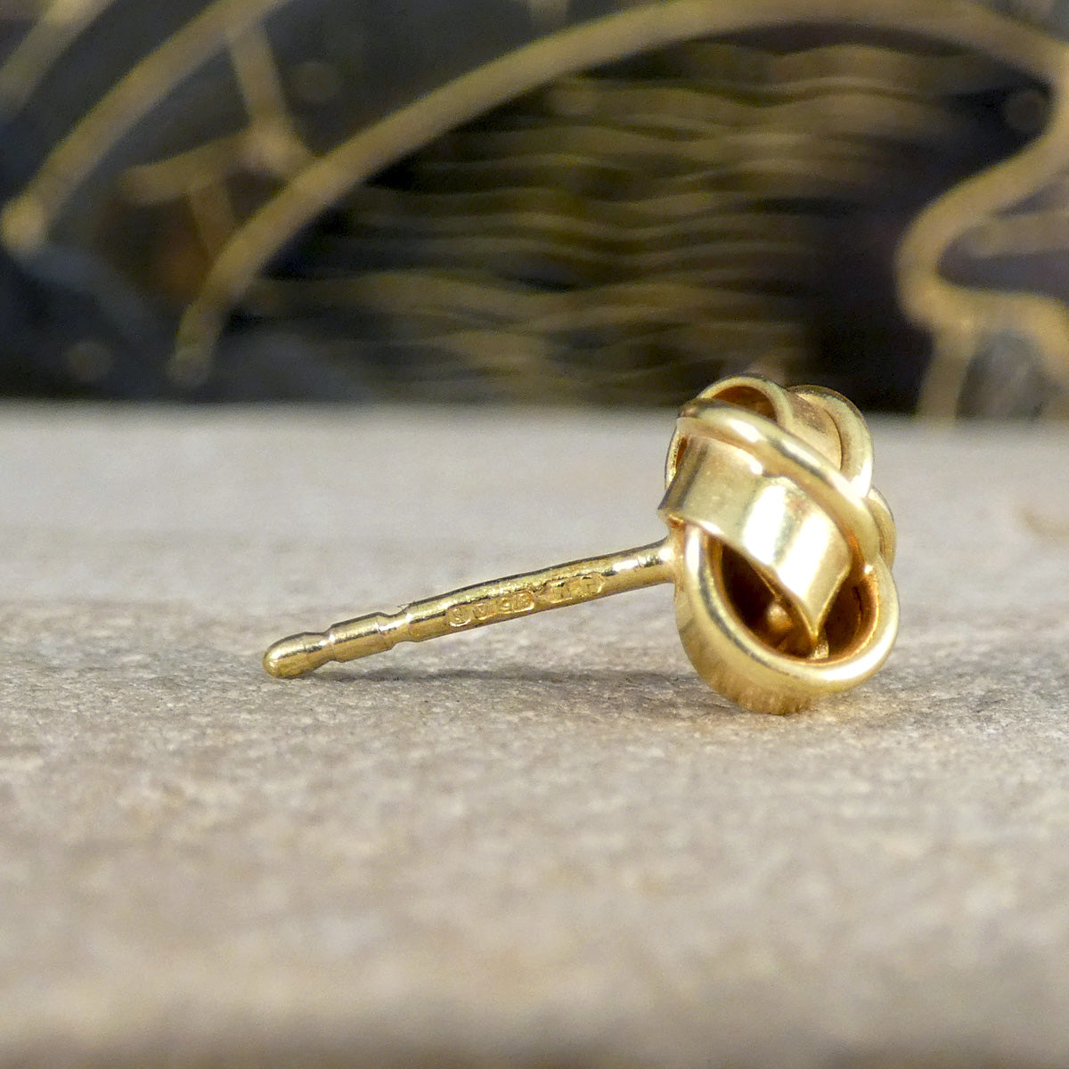 Close-up of a vintage knot earring in 9ct yellow gold, showcasing the detailed 1992 hallmark on the post, emphasising its authenticity and heritage.