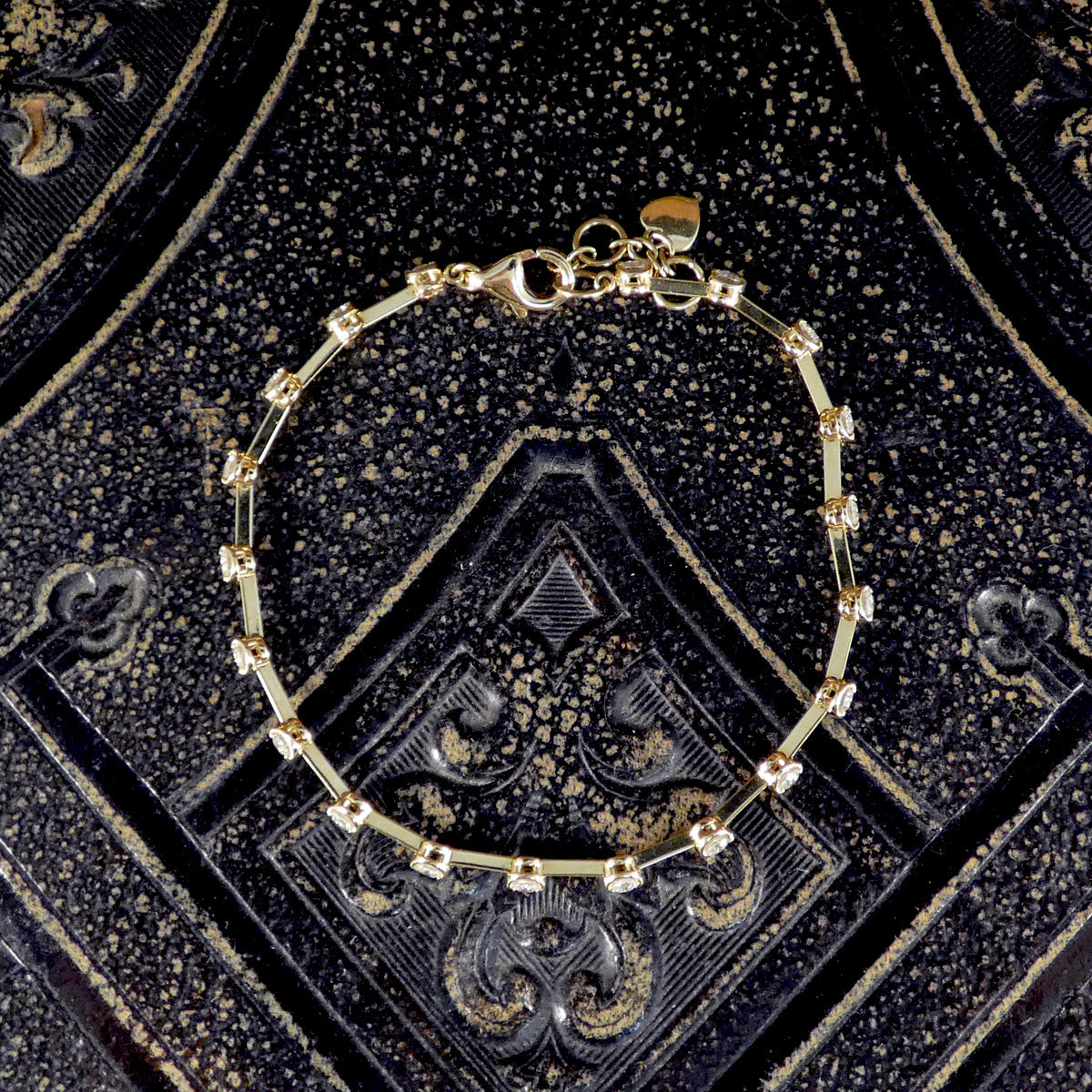 A full view of the 18ct yellow gold diamond bracelet, laid flat on a decorative surface to highlight its intricate design and sparkling diamonds.