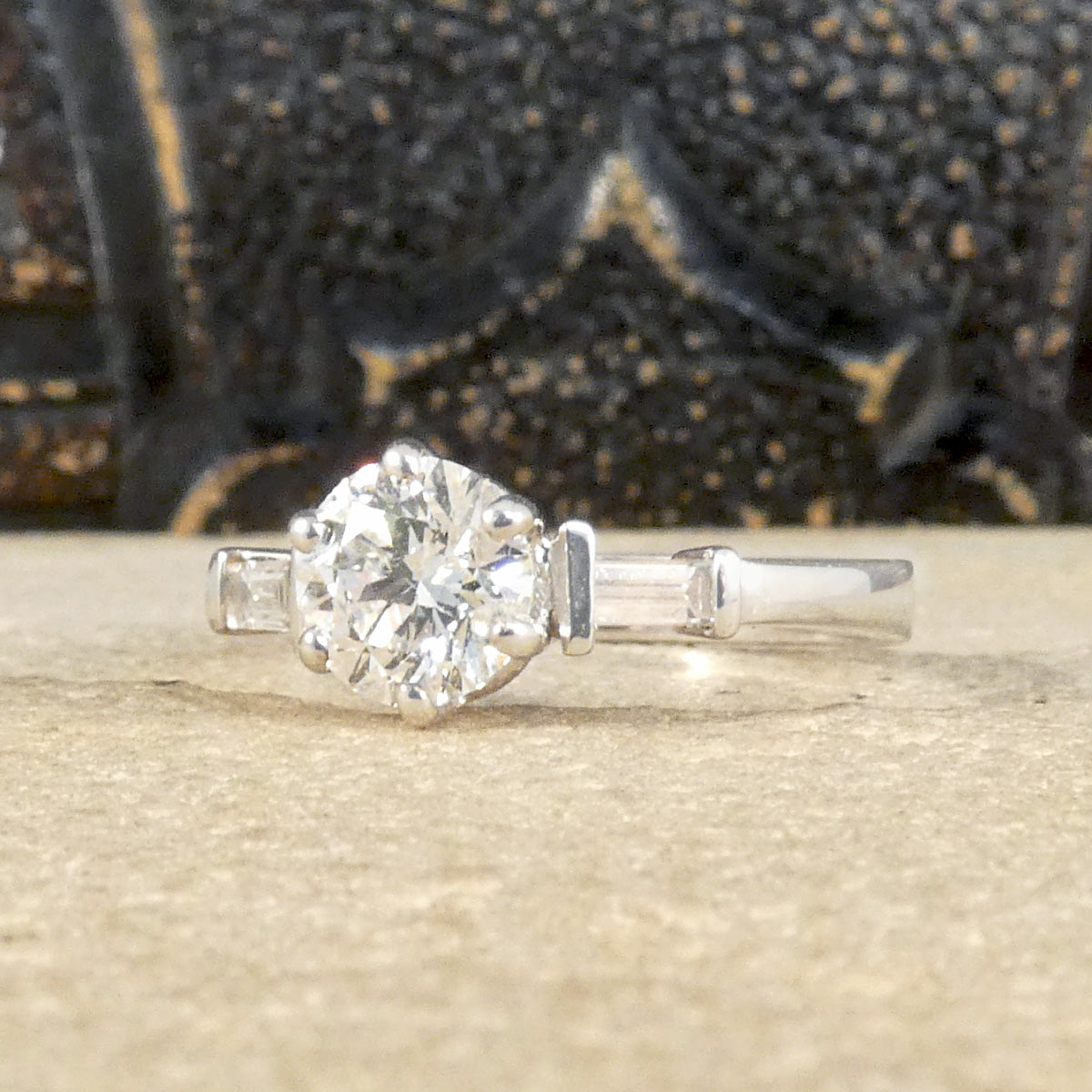 A classic brilliant cut diamond solitaire with baguette cut diamond shoulders in 18ct white gold. GIA certed diamond in a six claw setting, the perfect engagement ring.