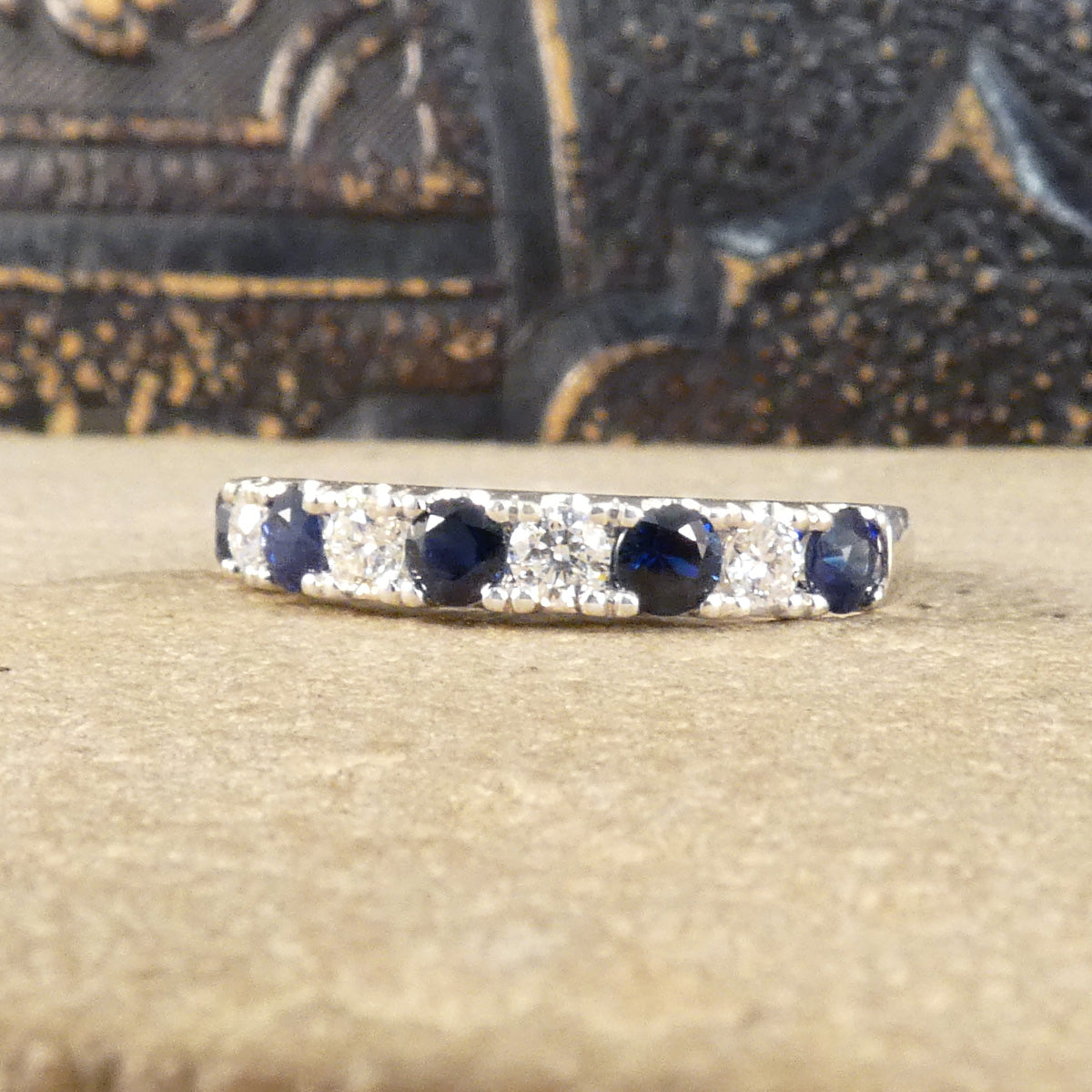 Alternating blue Sapphire and Diamond half eternity ring in white gold to complement the stones. Showing the stones spreading the whole width of the finger.