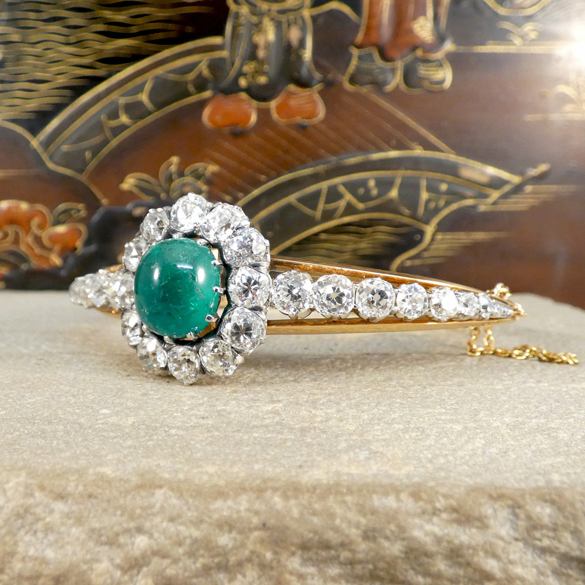 Stunning late Victorian cabochon emerald and diamond bangle, an exquisite example of antique English jewellery craftsmanship, featuring a vibrant emerald surrounded by old-cut diamonds, set in gold with exceptional attention to detail.