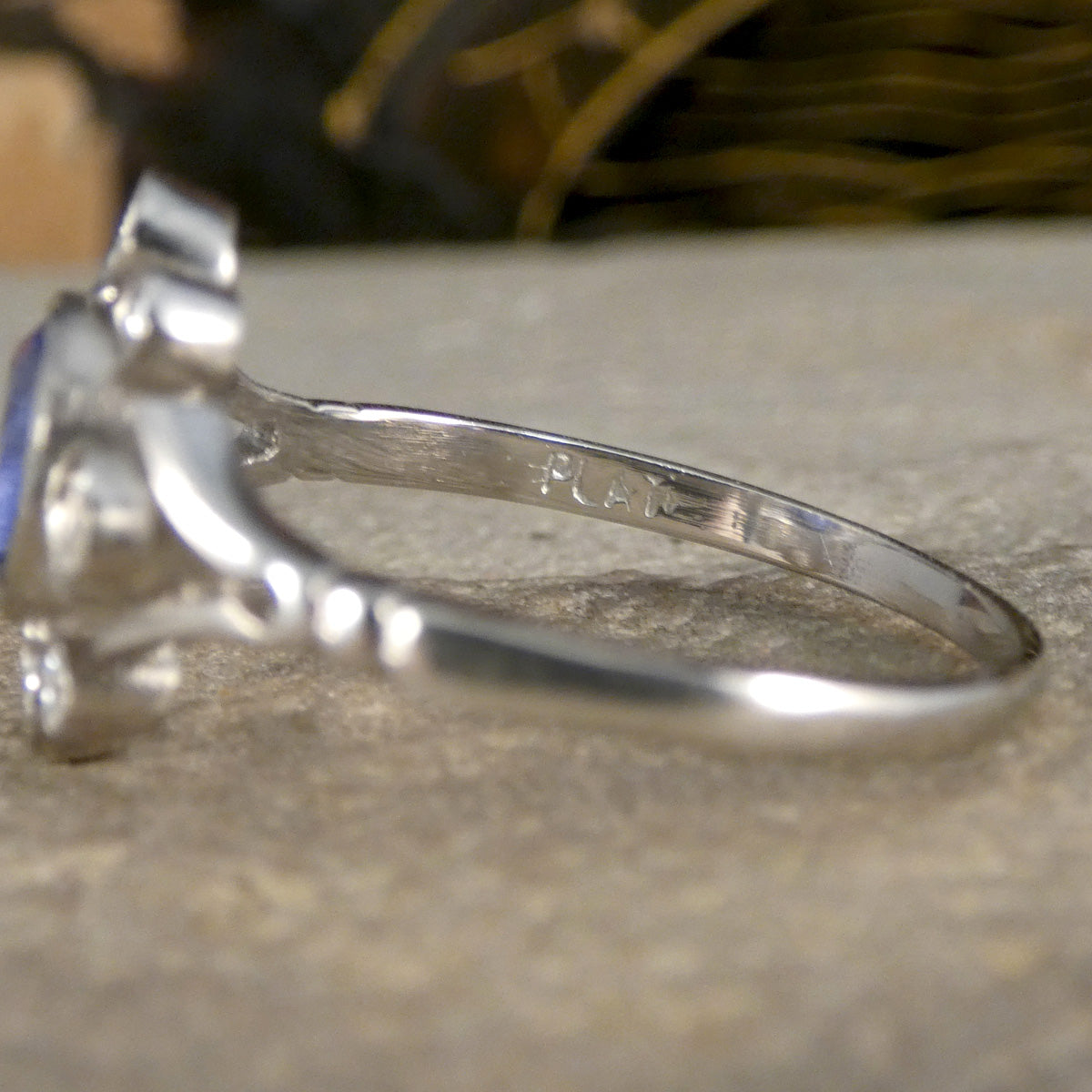 Close-up of the inner band of a platinum Sapphire and Diamond ring, highlighting the 'PLAT' hallmark engraving, showcasing authenticity and craftsmanship of the hallmarking technique in the 1920's.