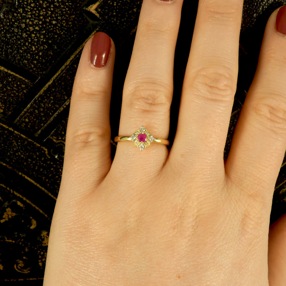 Ruby and Diamond Cross Section Illusion Set Ring in Yellow and White Gold showing a bright pink hue in the ruby and a gold cluster ring with a difference. Shown on the finger for view of how it would look when worn.