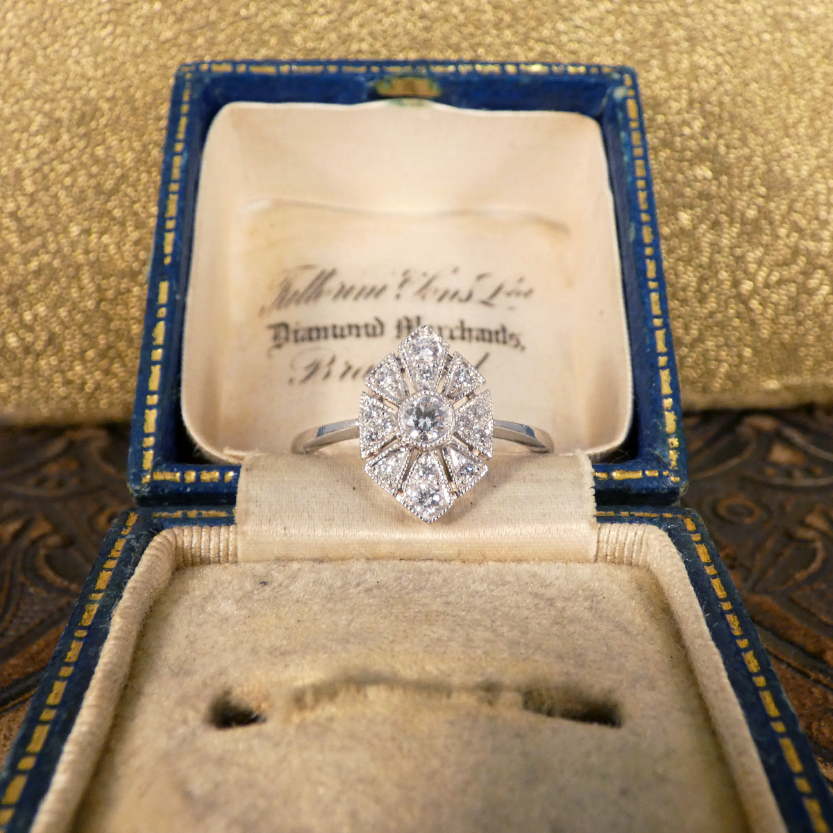 Art Deco-inspired replica ring crafted with exquisite craftsmanship in 18ct white gold, featuring intricate geometric patterns and a central diamond accent. Showcased in vintage box.