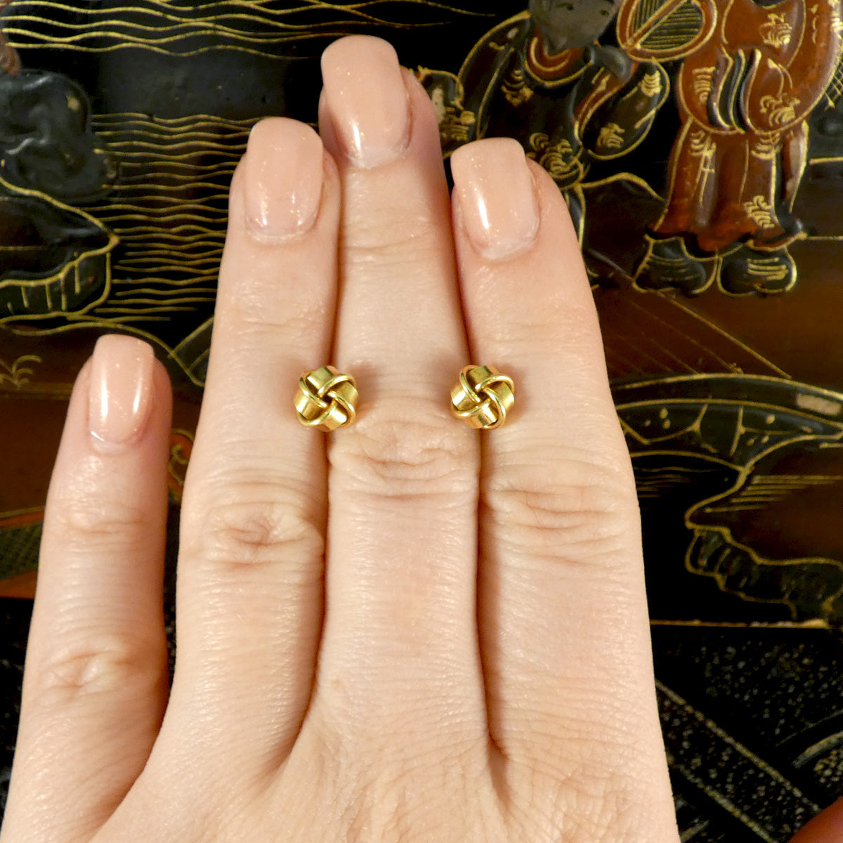 Vintage knot earrings in 9ct yellow gold displayed on fingers, showcasing their elegant size and intricate craftsmanship for a classic, timeless look.