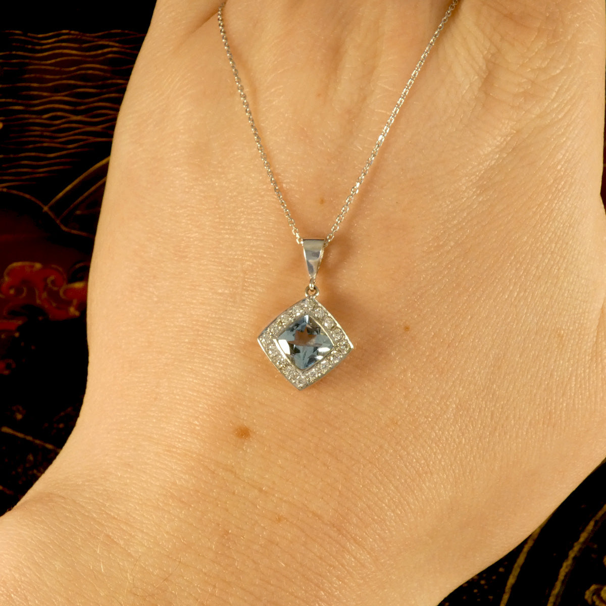 Strong blue Aquamarine and Diamond Cluster Pendant Necklace in Platinum with a solid platinum bail on a trace chain. Displayed on the hand to see what it would look like on.