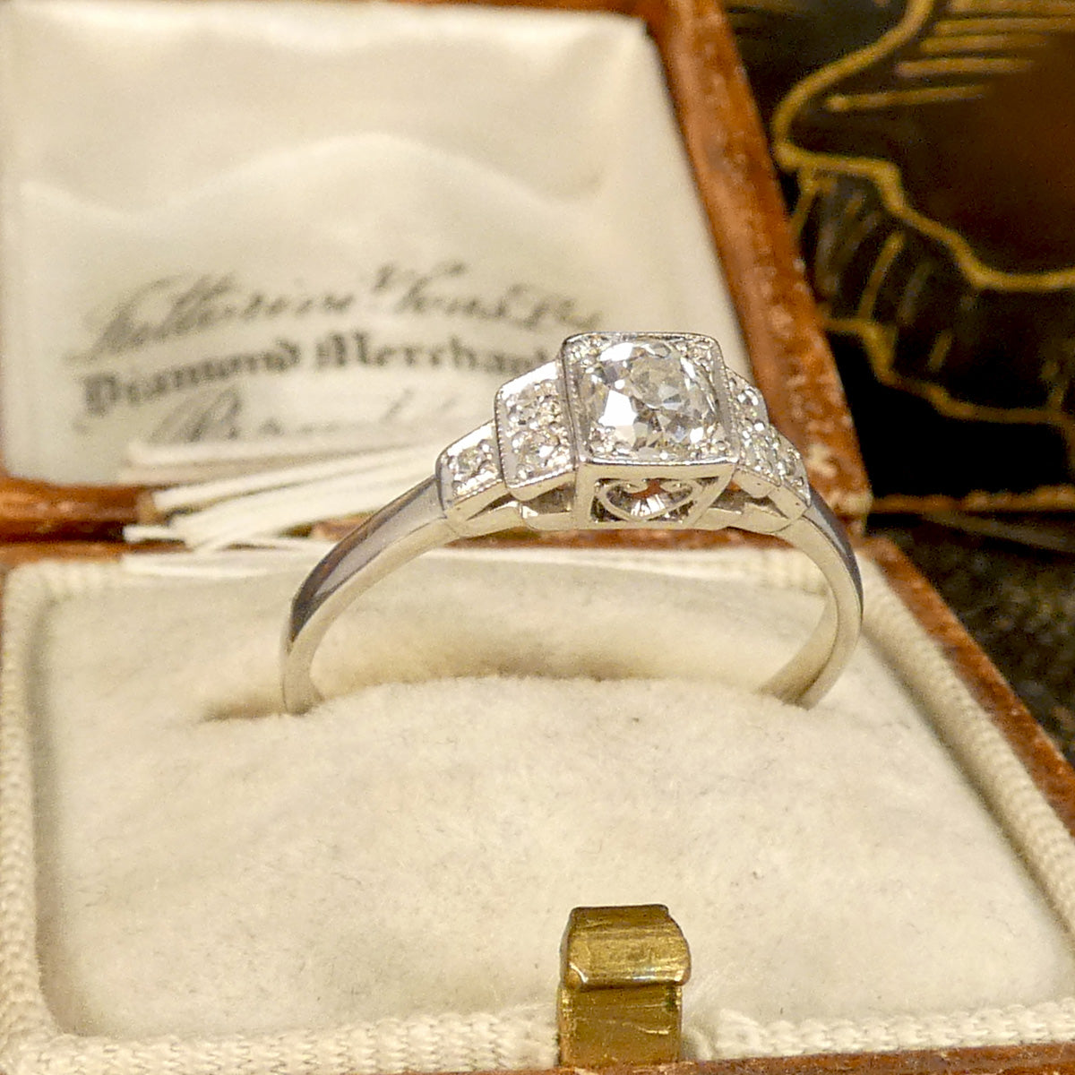 Vintage Art Deco Style Old Cut Diamond Ring with Diamond Staged Shoulders in Platinum. The perfect gift or engagement ring for anyone who likes a vintage beautiful piece. Displayed in vintage bow with heart scroll detail in gallery.