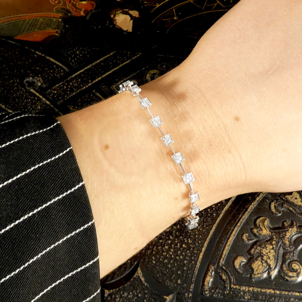 8-carat white gold tennis bracelet featuring 1.50 carats of square bezel-set diamonds, elegantly worn on the wrist. The sleek and modern design offers a comfortable and adjustable fit, making it a luxurious and versatile accessory for any occasion and able to gift without knowing the same of arm.