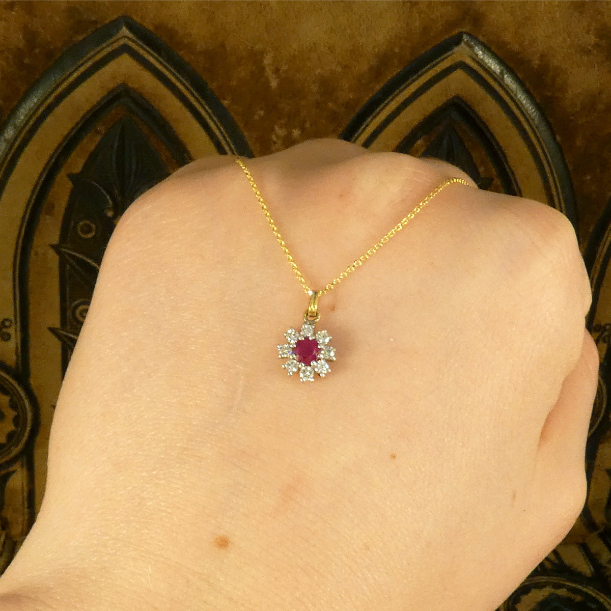 Ruby and Diamond Flower Cluster Pendant Necklace in 18ct Yellow and White Gold shown on the back of a hand to show a better size ratio and contrast.