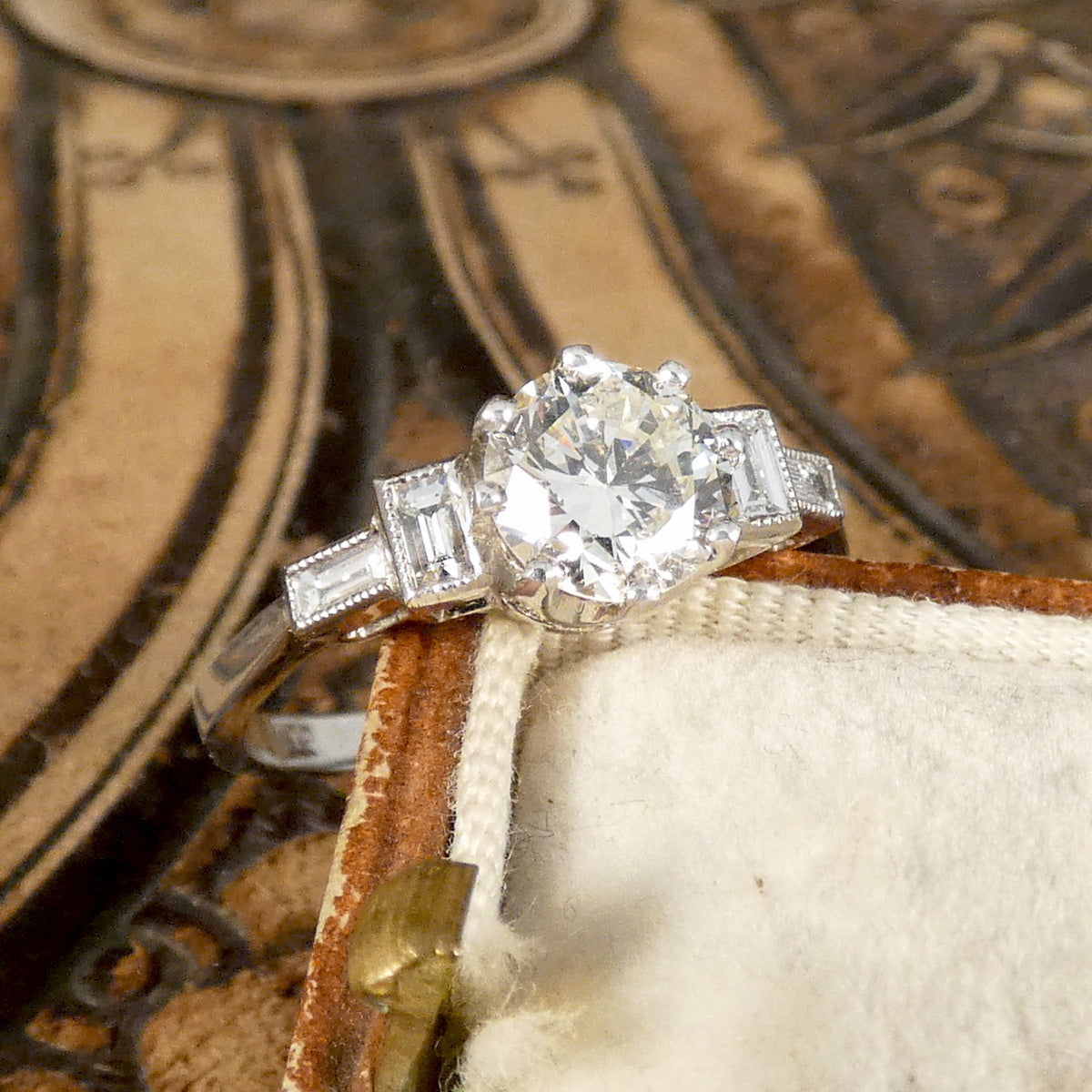 Art Deco homage engagement ring with an early brilliant cut centre and baguette cut diamond shoulders set in Platinum.