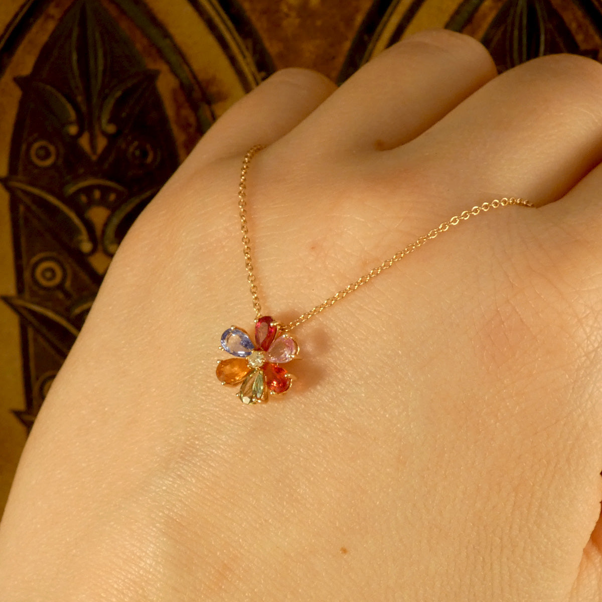 Multi Coloured Sapphire and Diamond Flower Cluster Pendant Necklace in 18ct Rose Gold. Bursts of colour is a dainty and elegant necklace. Shown on the back of a hand to see how it would look.