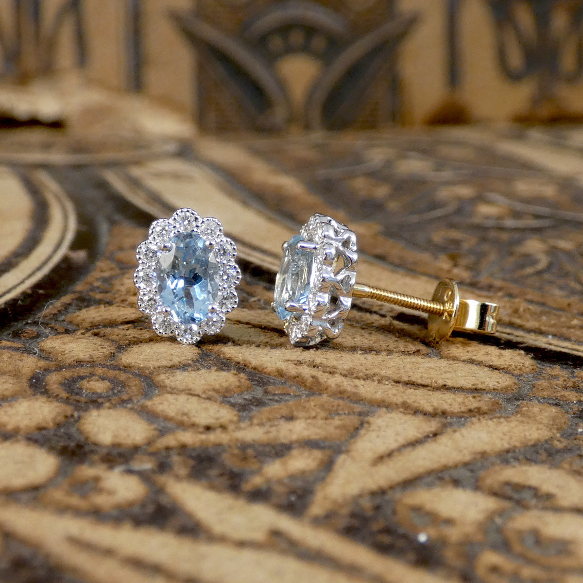 Aquamarine and Diamond cluster earring sin 18ct white and yellow gold. Light to medium oval cut aquamarines in a four claw setting with smaller brilliant cut diamonds creating lots of sparkle. March birth stone and great gift.