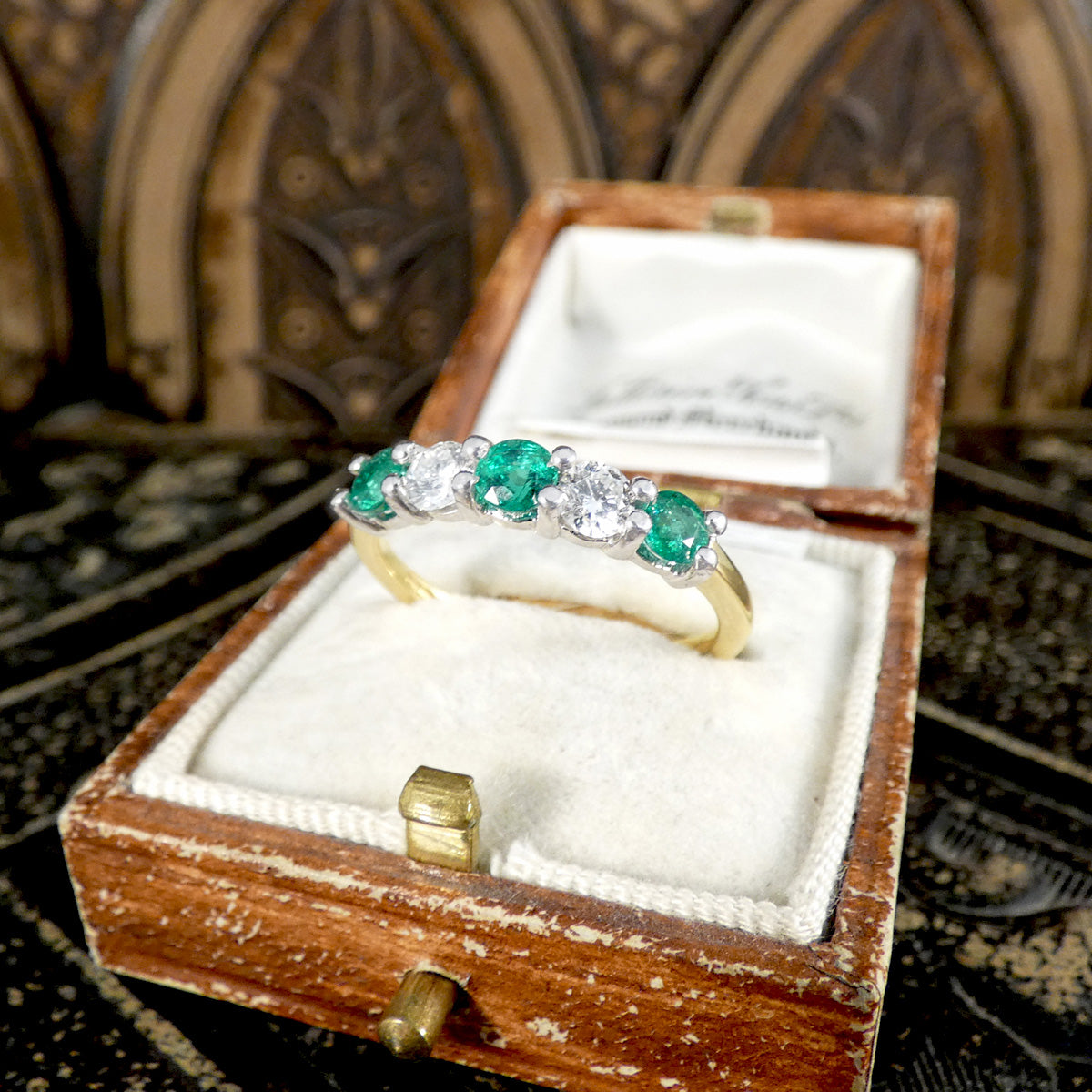 Featuring bright and vibrant emeralds sandwiching bright and clear diamonds in a five stone band ring.